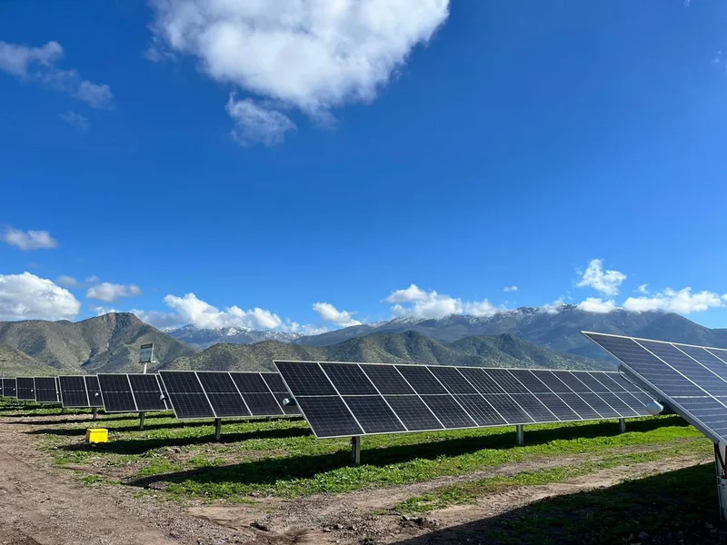 Hileras de paneles solares frente a la cordillera de los Andes nevada