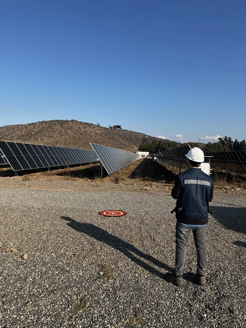 Operario de Solarik con casco y equipo de protección en terreno, junto a las hileras de paneles
